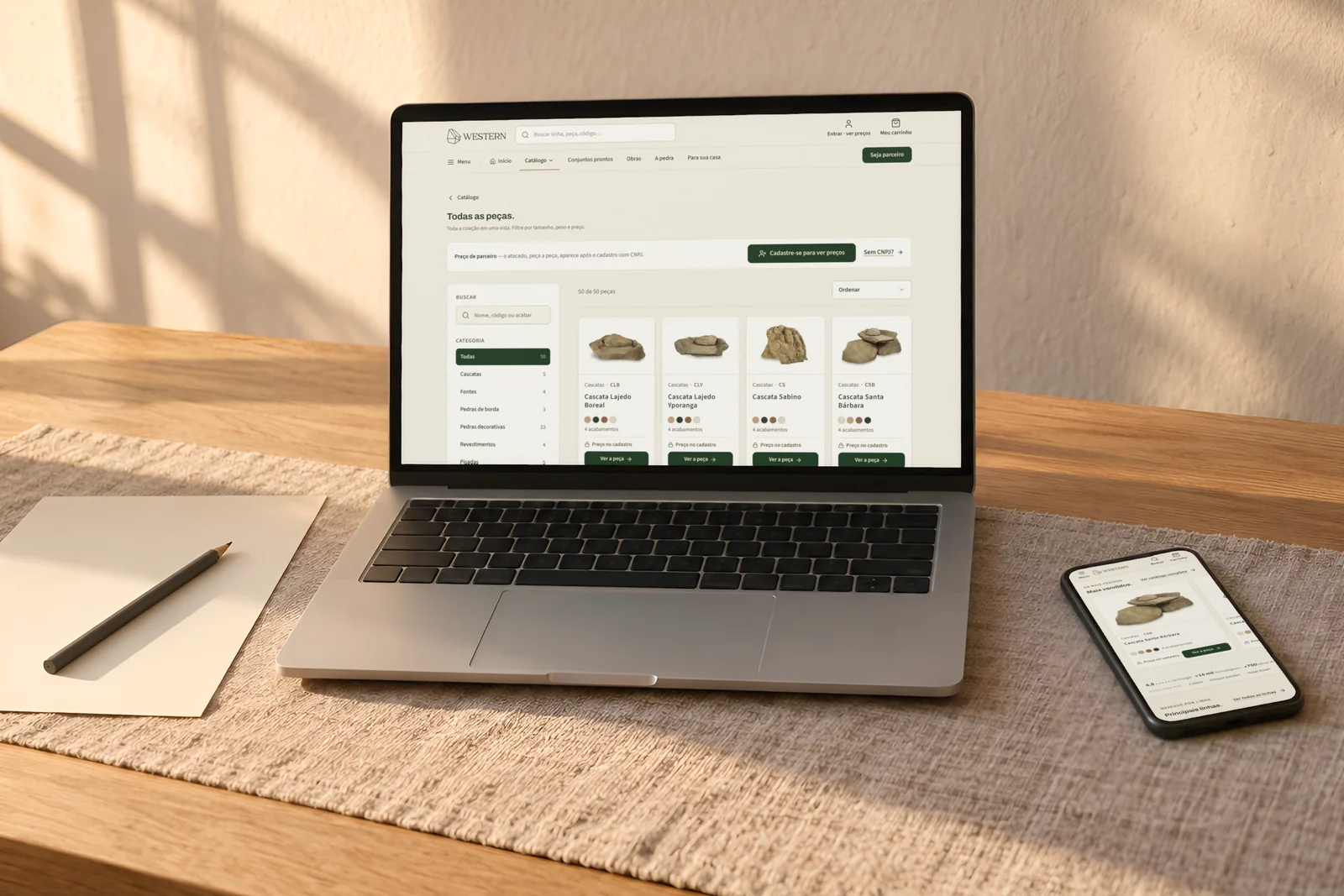 Notebook e celular com a WesternStore aberta numa mesa de madeira, ao fim da tarde