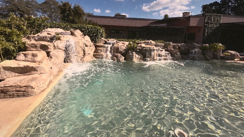 A obra pronta: a cascata de pedra e a praia de areia em volta da piscina, com a casa ao fundo