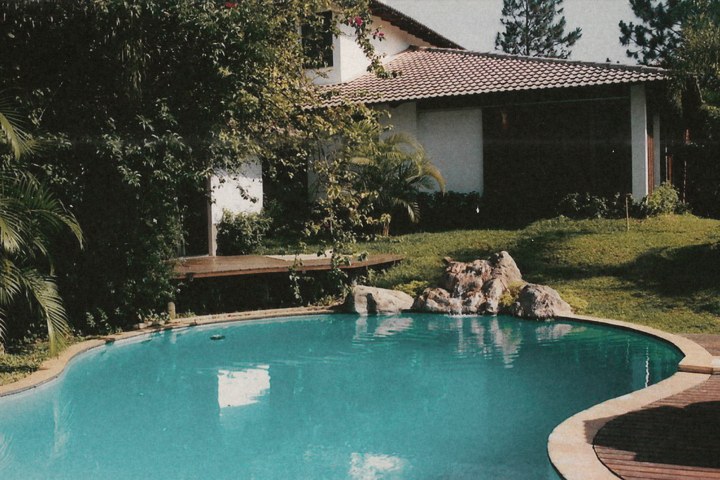 Piscina com pedras junto a uma casa com jardim, em 1994