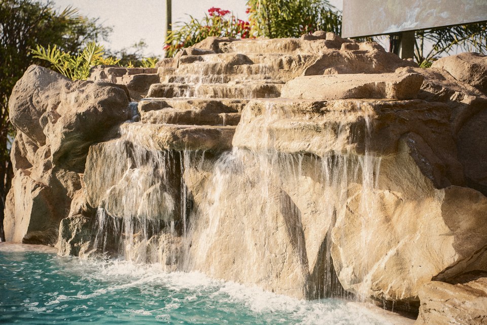 Uma cascata de pedra caindo numa piscina