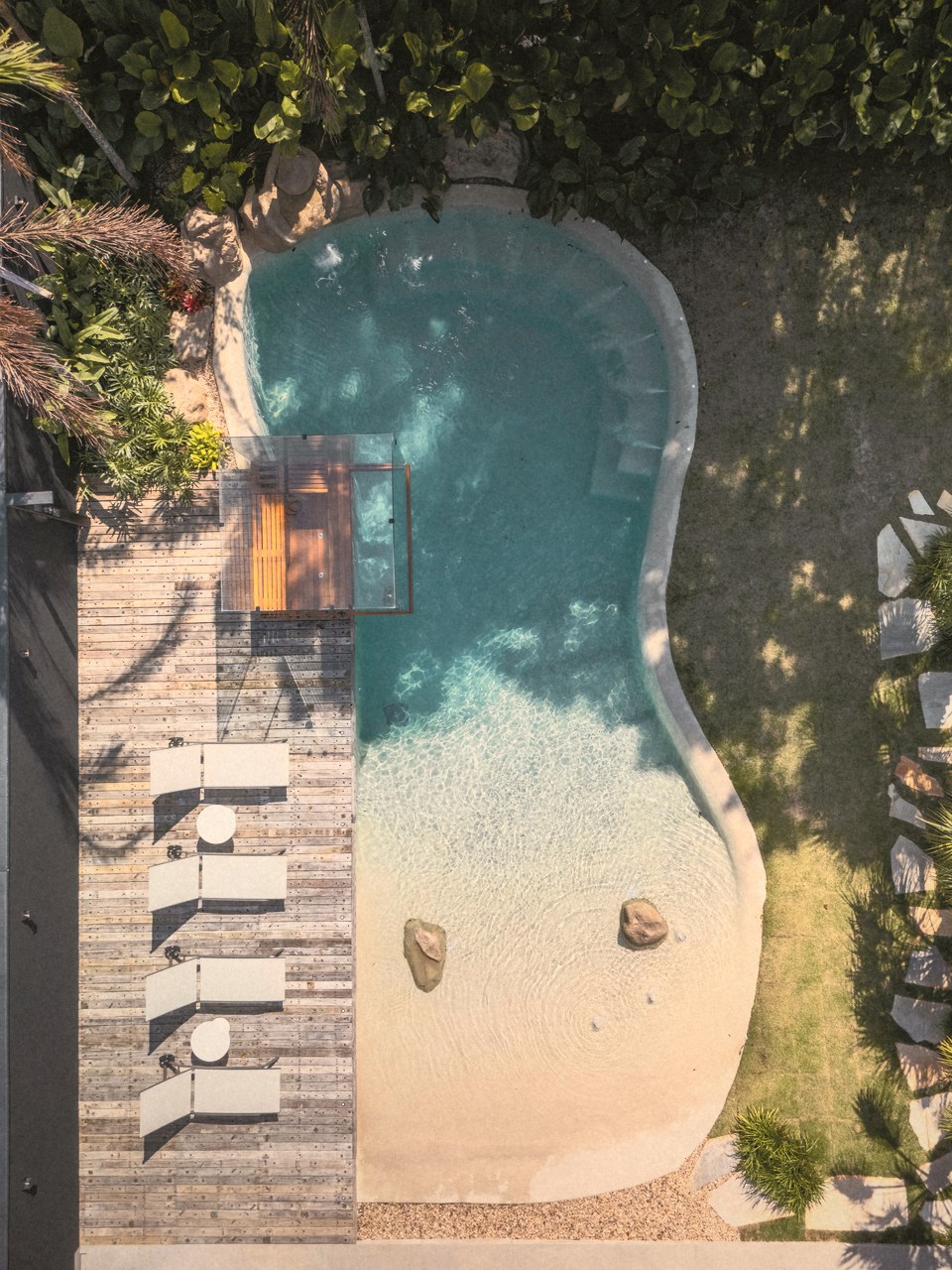 Uma piscina natural vista de cima, com a praia de areia e o deck