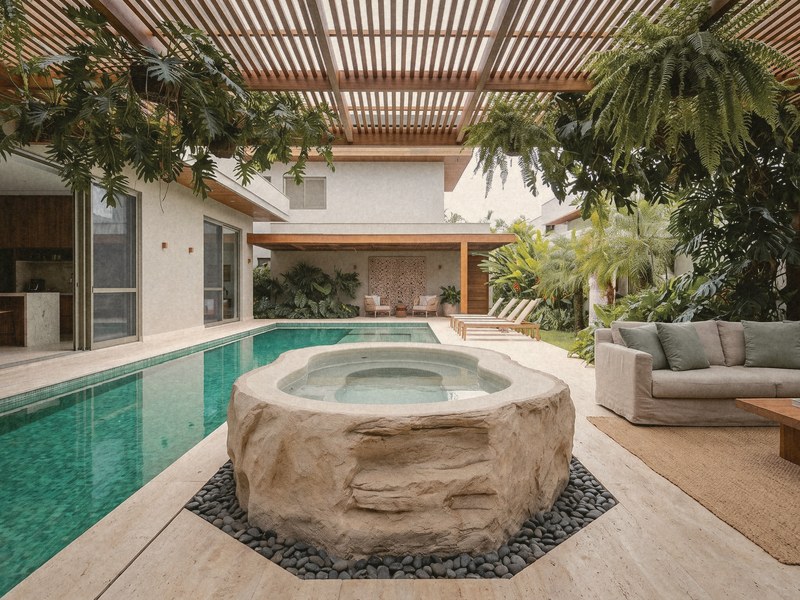 O UNA ao lado da piscina, sob o pergolado, com a área de estar