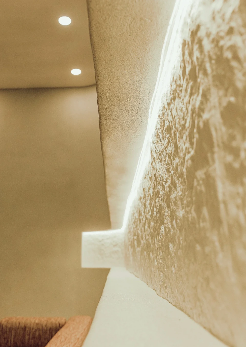 Parede texturizada e luz de cava: a pedra vira acabamento contínuo.