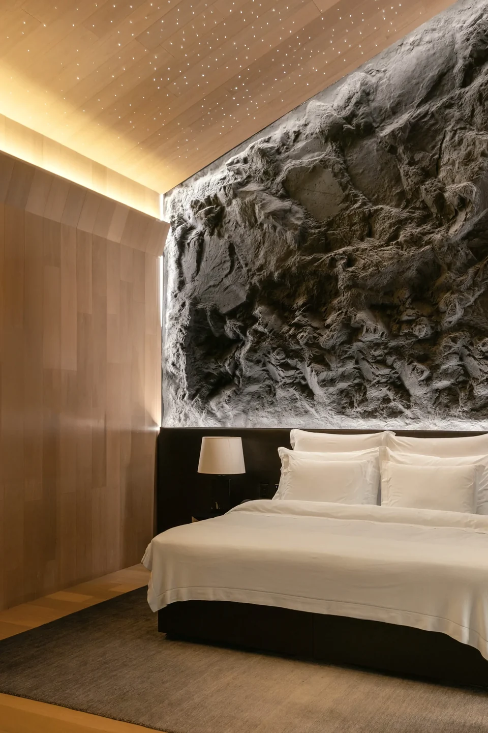 Quarto com uma parede inteira de rocha moldada iluminada de cima