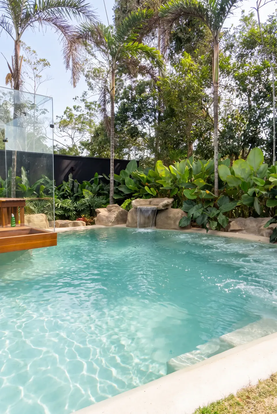 Piscina de borda orgânica e água turquesa no jardim tropical
